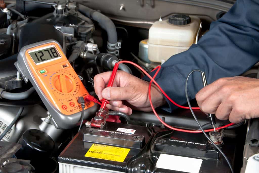 Auto mechanic checking car battery voltage