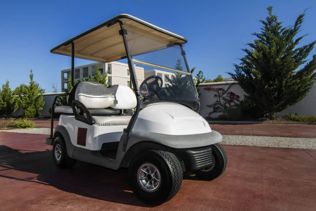  Close up view of a white golf cart parked on the road.