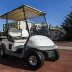 Close up view of a white golf cart parked on the road.