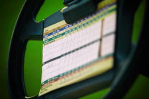 close up of golf score card on the steering wheel of golf cart on fairway.