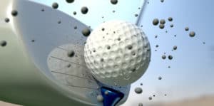 An extreme close up of a golf ball being hit off its tee with a club on a blue sky background