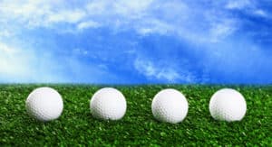 Golf balls on green grass against blue sky background