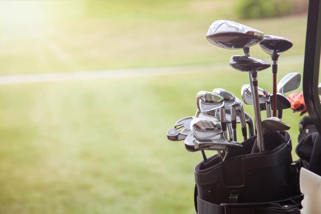 set of golf clubs over green field background