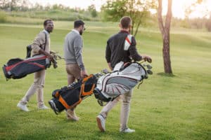 men walking on golf course carrying golf bags