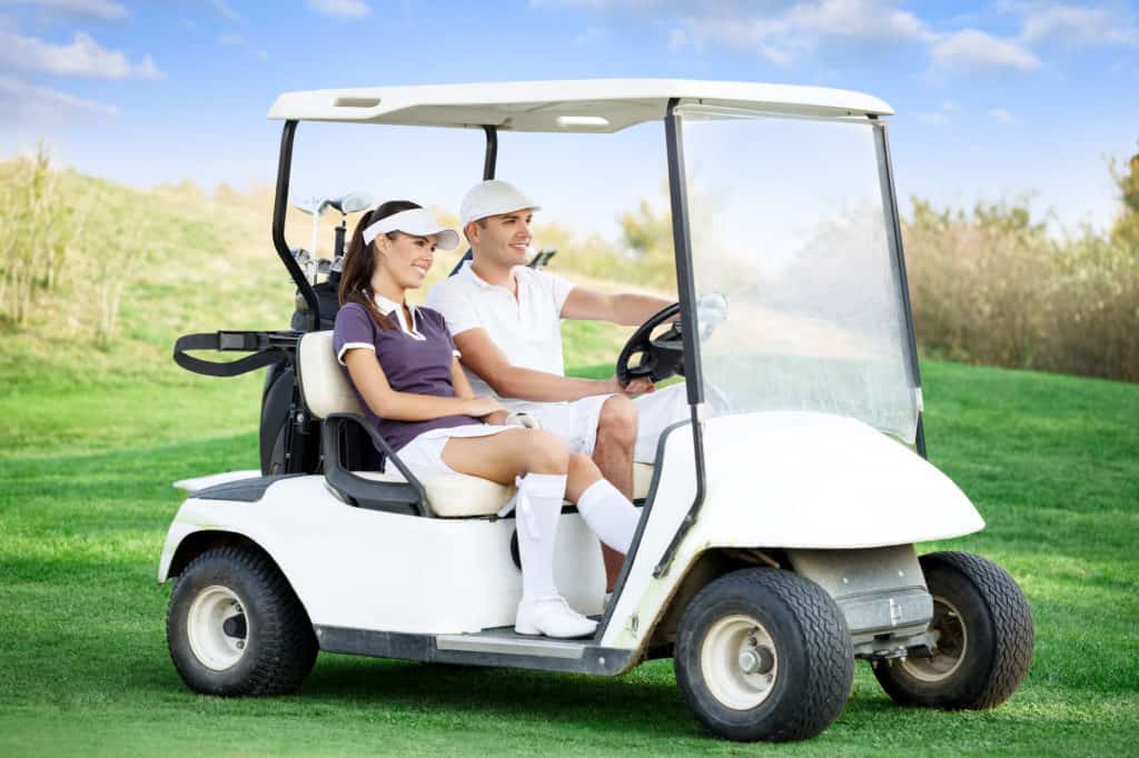 Young couple driving golf cart