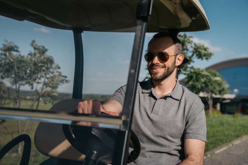 man driving looking at golf cart windshield