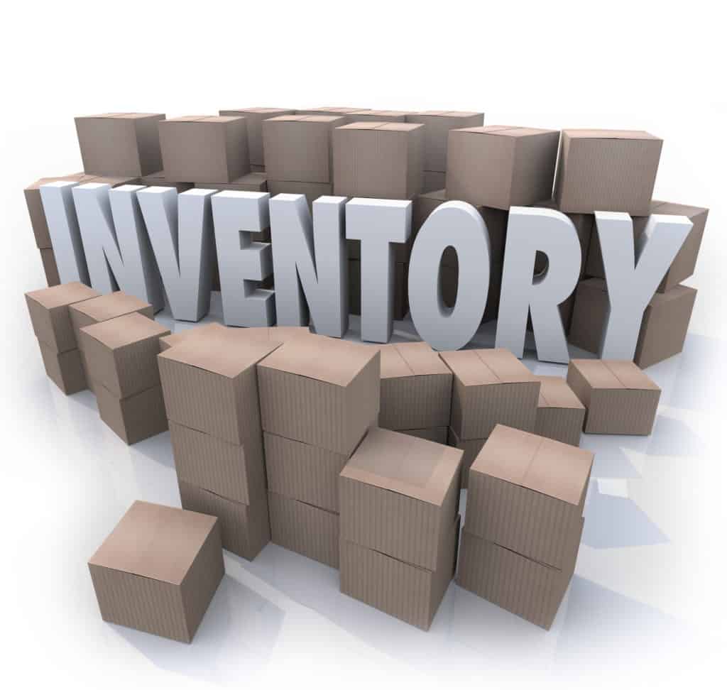 A surplus or oversupply of products in cardboard boxes in a stockroom or warehouse with the word Inventory in the mess of box piles and stacks