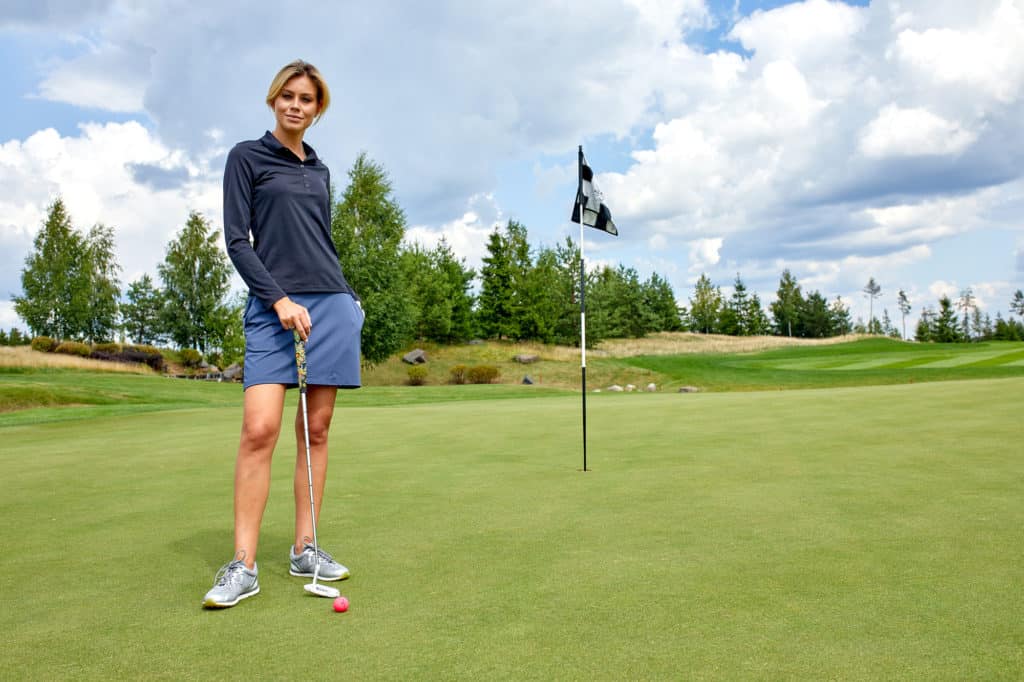 Portrait of a beautiful woman playing golf on a green field outdoors background. The concept of golf, the pursuit of excellence, personal excellence, royal sport