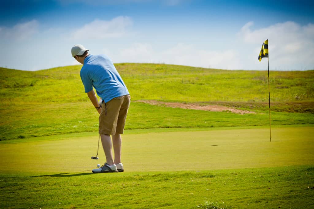 Young male golfer putting the golf ball on the putting green