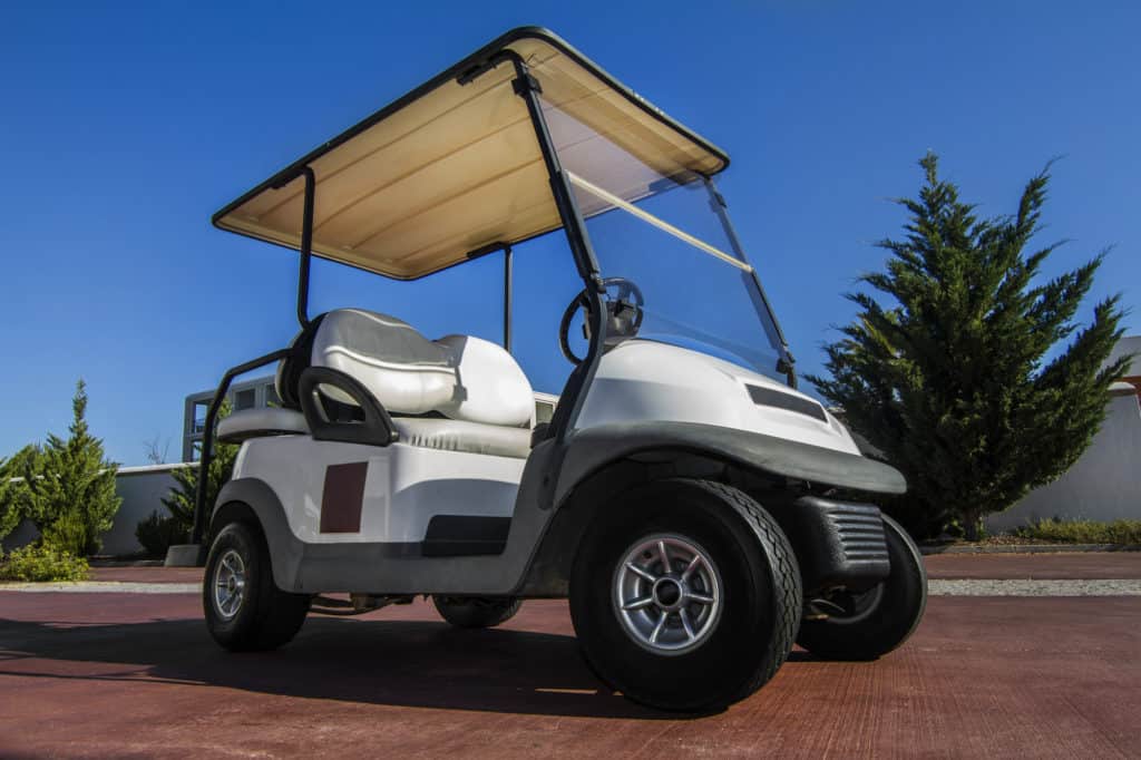 Close up view of a white golf cart parked on the road.