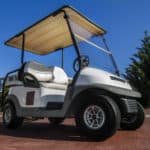 Close up view of a white golf cart parked on the road.