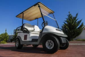 Close up view of a white golf cart parked on the road.