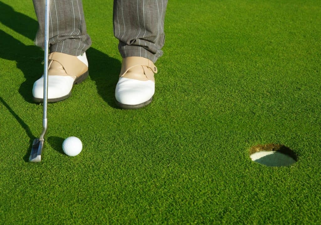 Golf green hole course man putting ball inside short putt