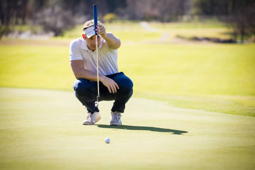 golfer lining up his shot on putting green