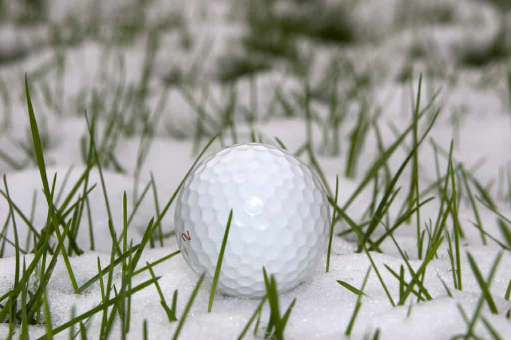 a lone single golf ball in the snow covered grass in Ireland at winter