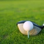 Golf tee ball club driver in green grass course closeup