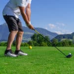 Photo of a male golfer about to tee off on the golf course.