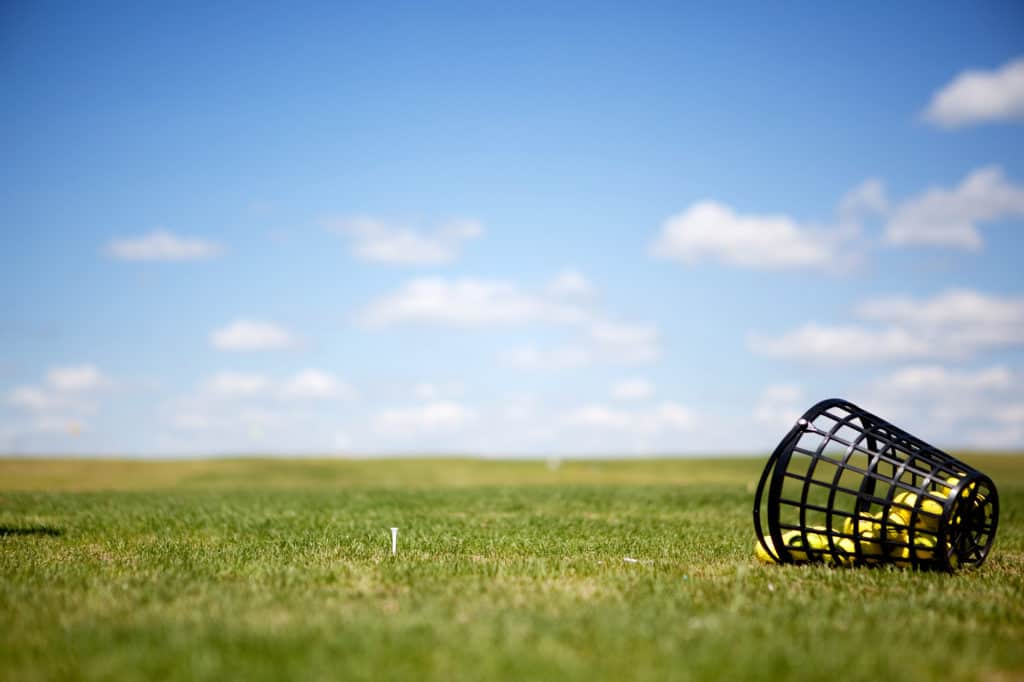 A tee and yellow golf balls on a driving range