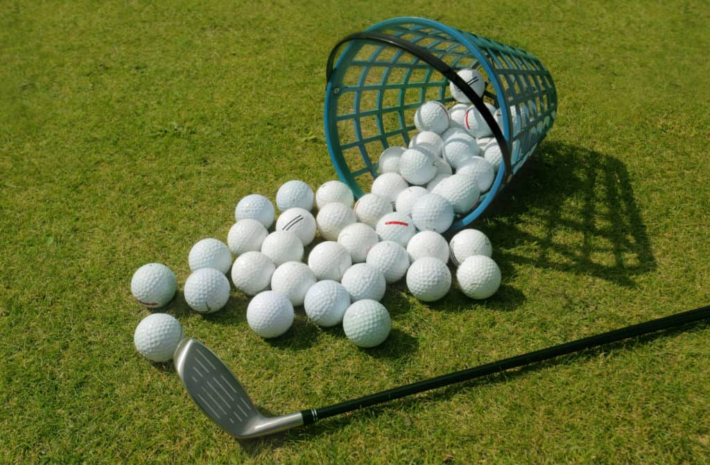 Golf balls pouring out of basket onto grass