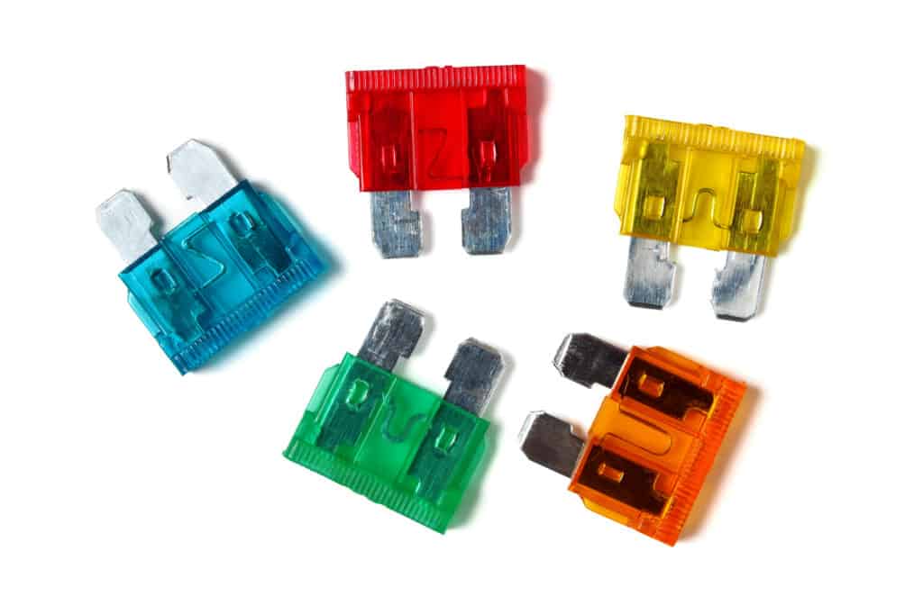 Set of colorful regular car fuses on white background.