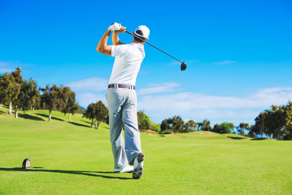 Golf player teeing off. Man hitting golf ball from tee box with driver