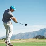 Golfer hitting tee shot with driver from teebox, on beautiful course and good strike