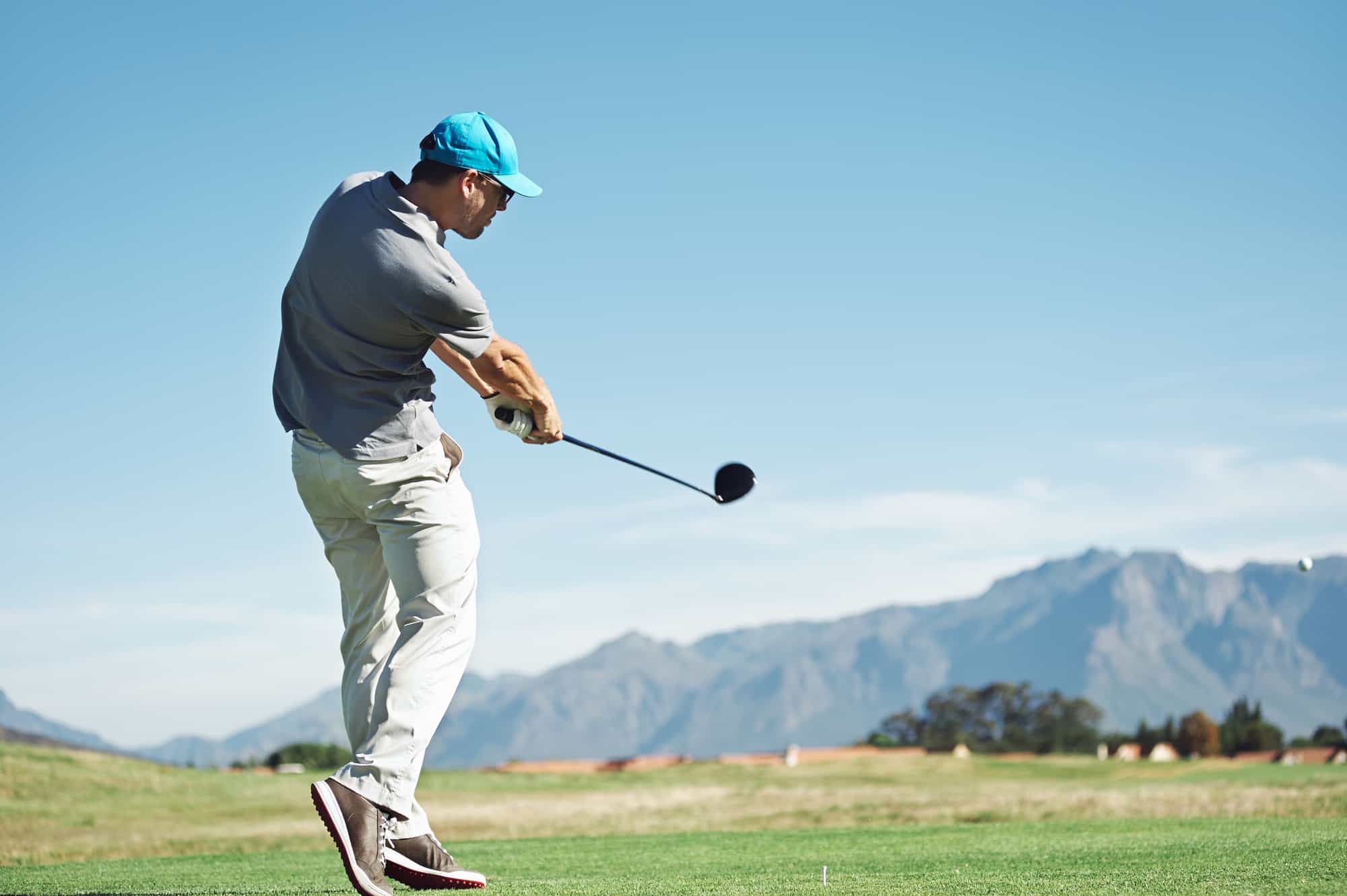 Golfer hitting tee shot with driver from teebox, on beautiful course and good strike