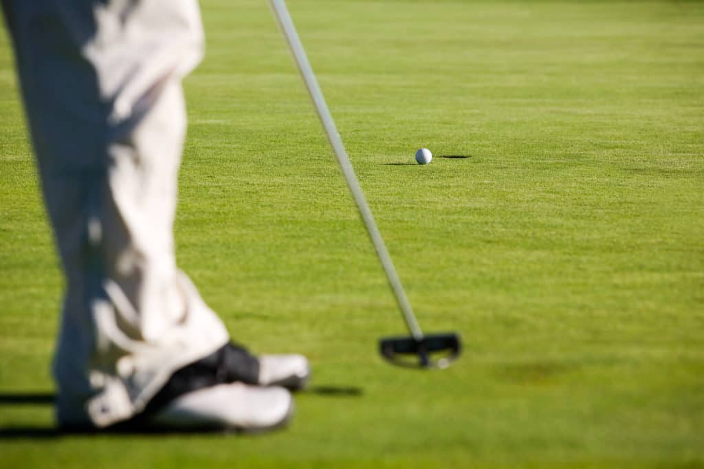 Golfer putting, selective focus on golf ball