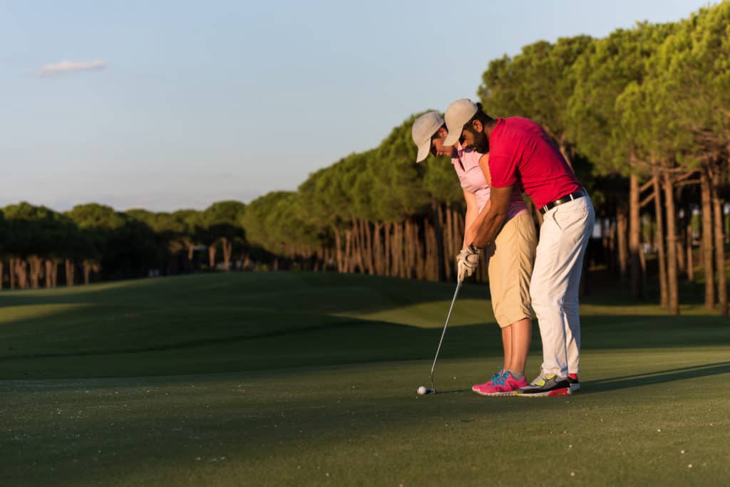 male golf instructor teaching female golf player, personal 