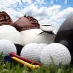 Golf shoes and equipment sitting on grass with a bright blue sky in the background