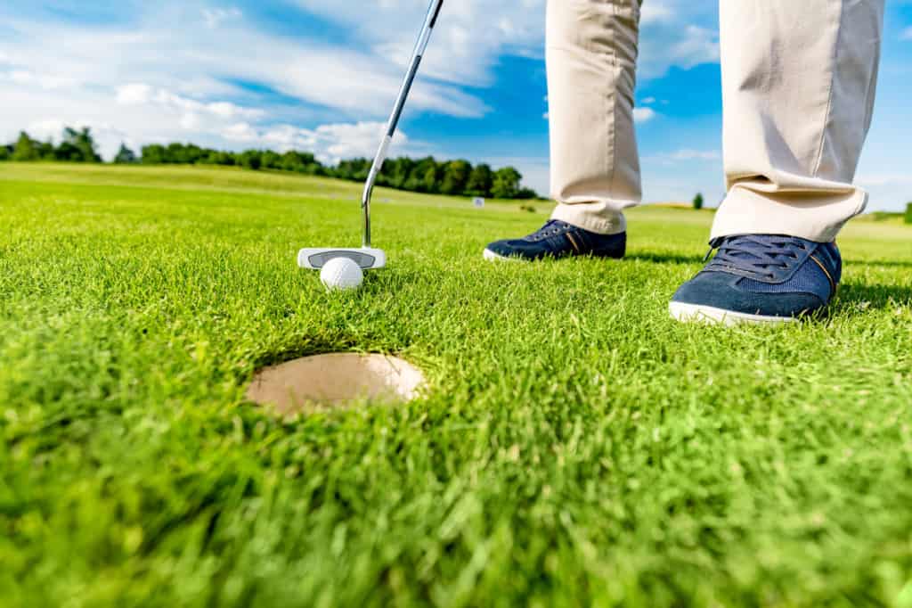 Golfer putting ball in the hole on a golf course close up. Focus on the ball.