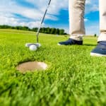 Golfer putting ball in the hole on a golf course close up. Focus on the ball.
