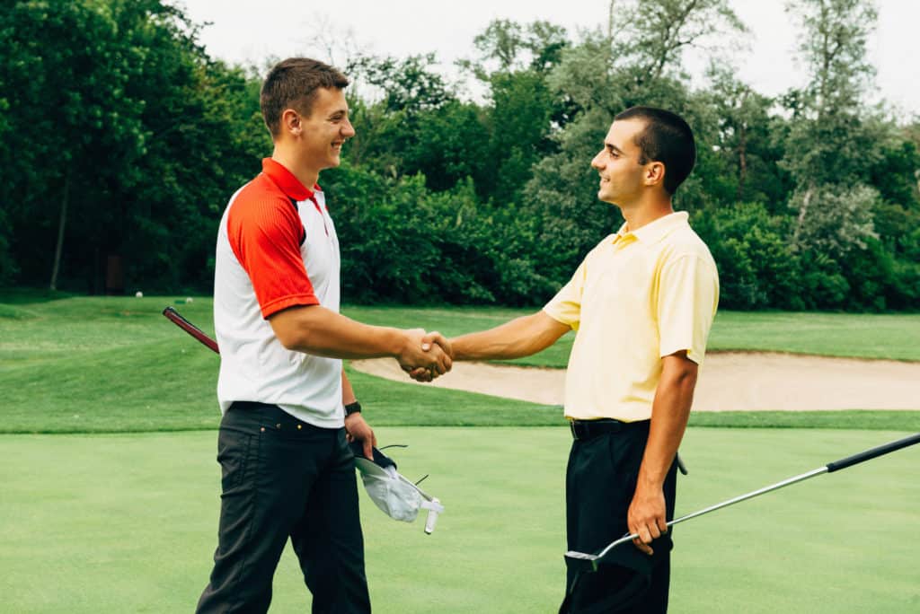 Friends shaking hands after golf game. 