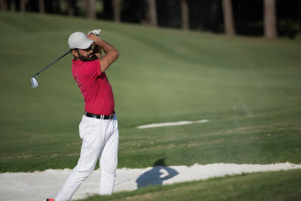 golf player shot ball from sand bunker at course