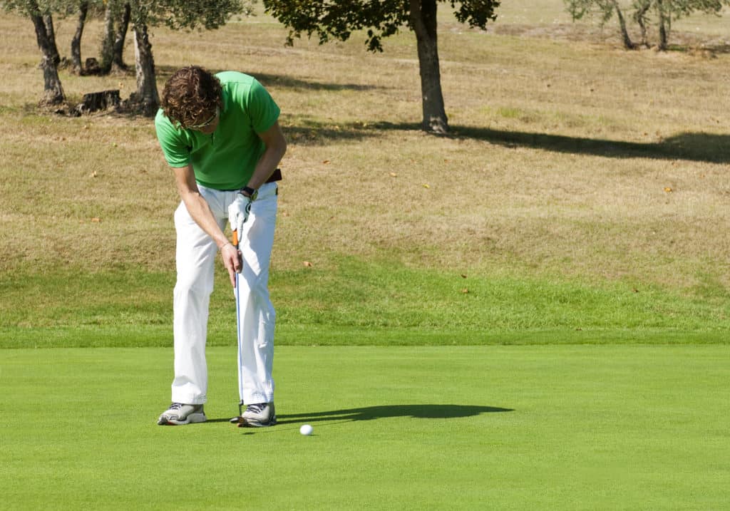 Golfer concentrating for a put on the green of a colf course