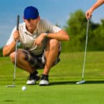 Young golf player on course putting, he aiming for his put shot