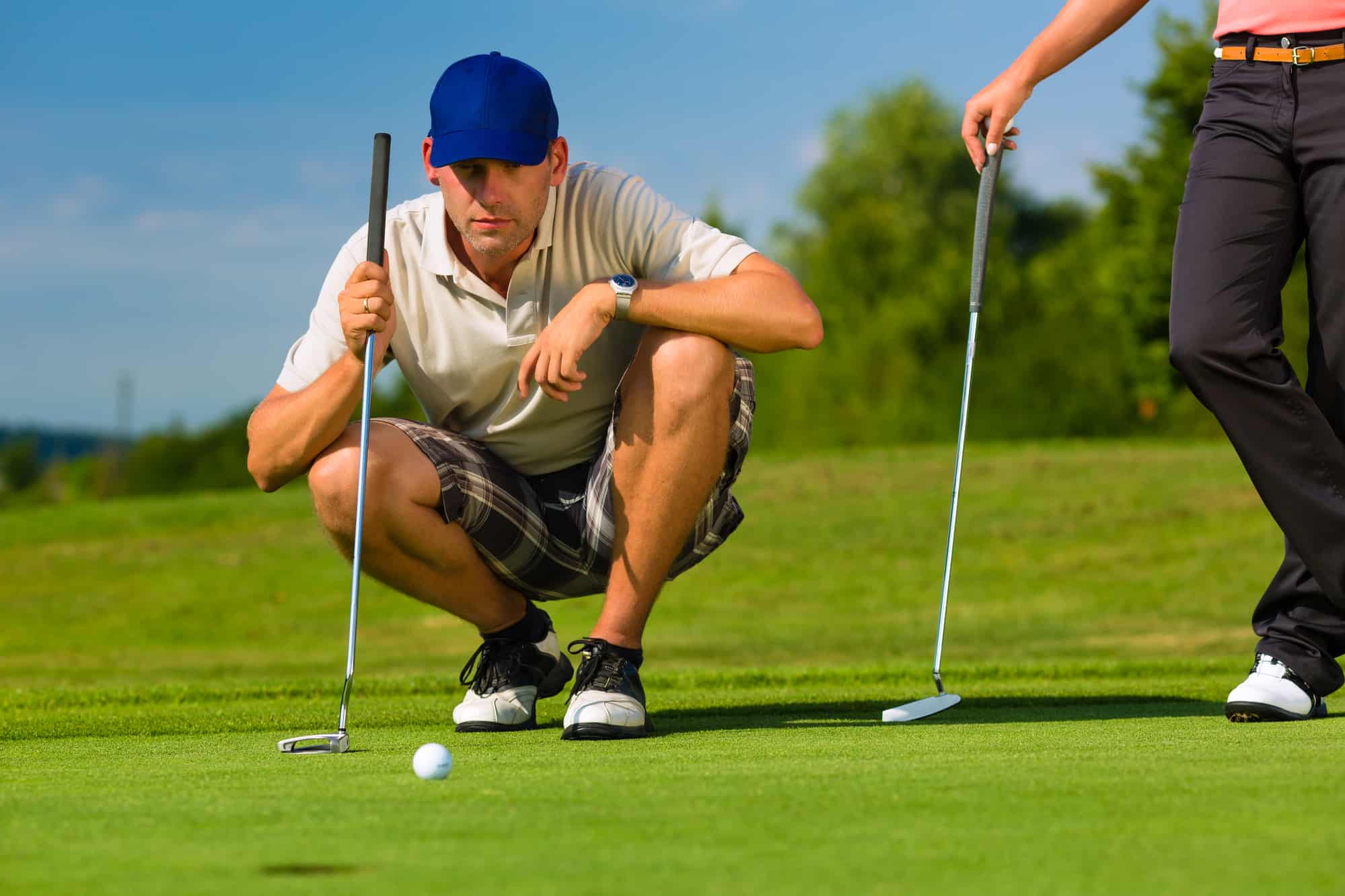 Young golf player on course putting, he aiming for his put shot