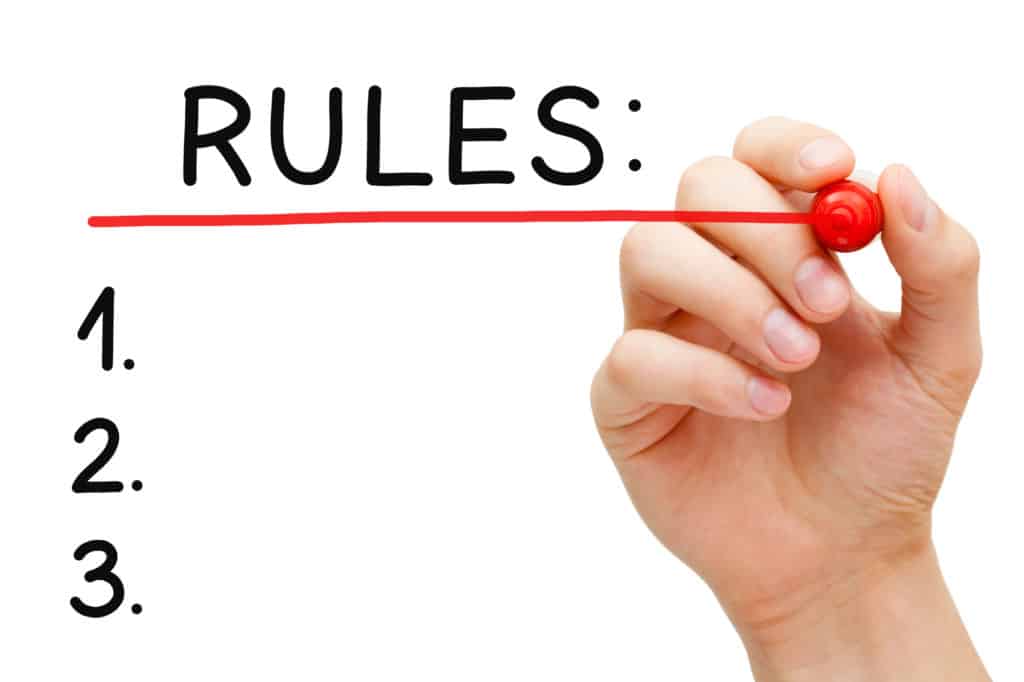 Hand underlining Rules with red marker on transparent wipe board.