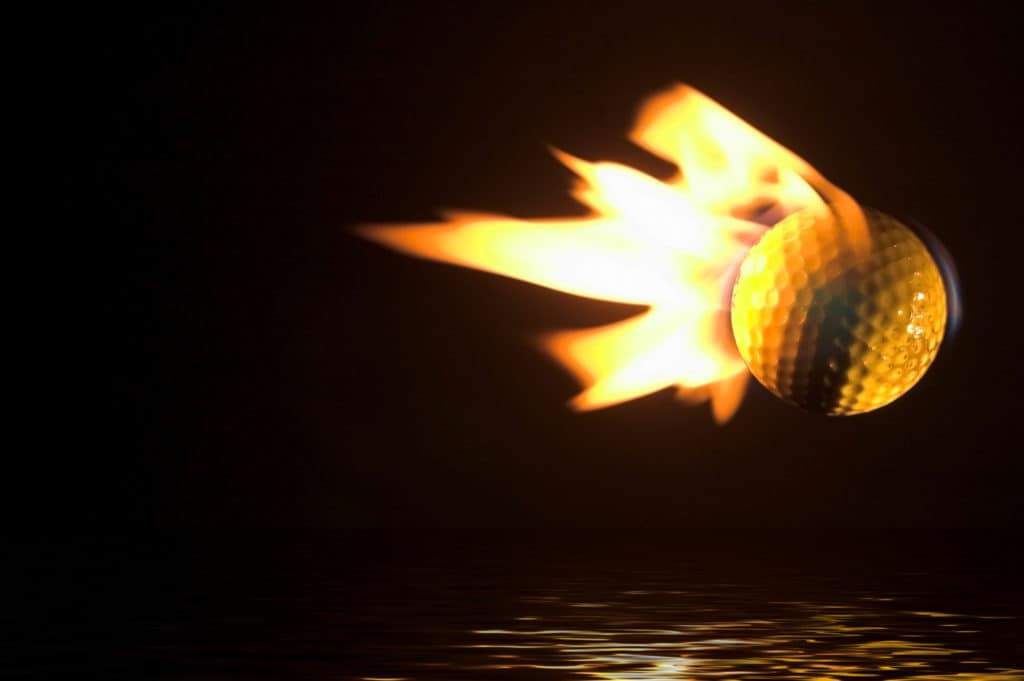 A flaming golf ball flying over a water hazard.