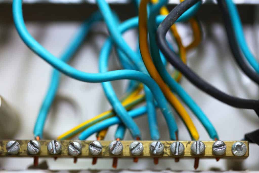 Electrical installation. Close up electric wires hanging on wall construction building site.