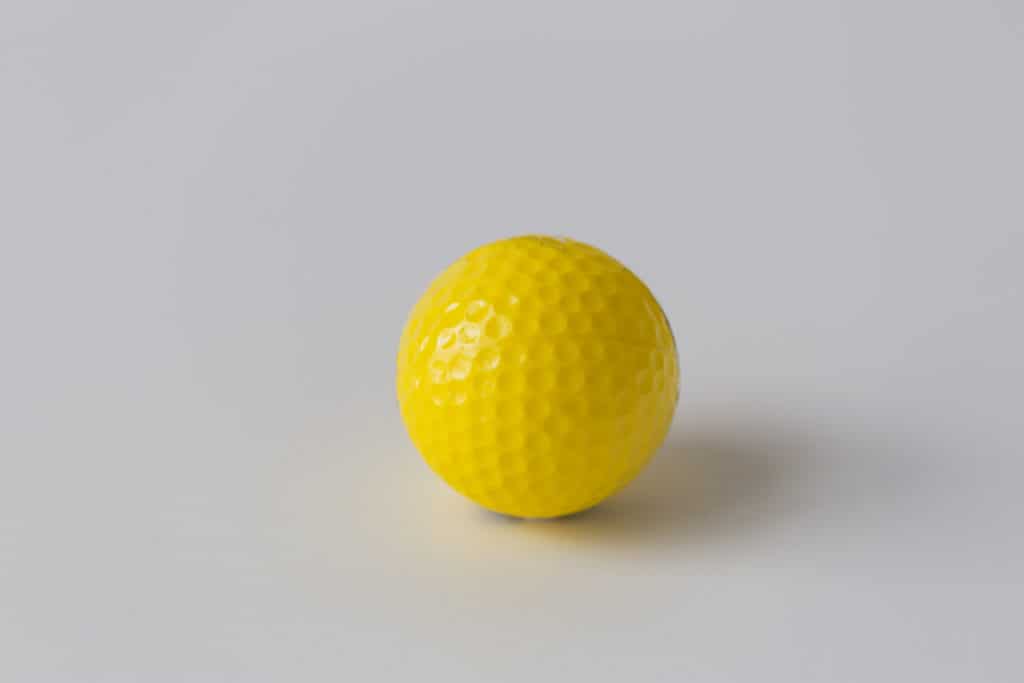 sport, fitness, game, sports equipment and objects concept - close up of yellow golf ball