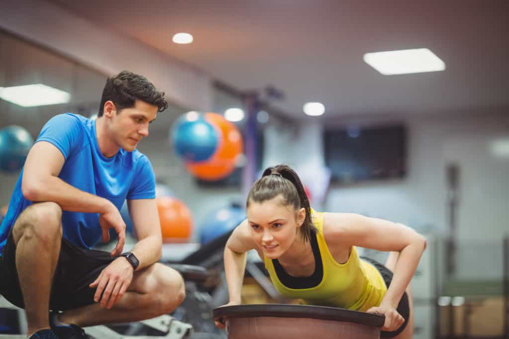 Fit woman working out with trainer at the gym