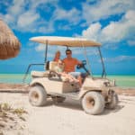 Dad and his two daughters driving golf cart on a tropical beach