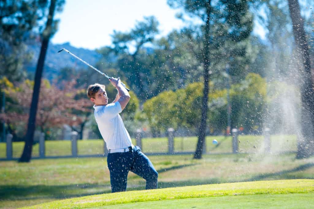 image of a golfer playing a chip shot onto the green on a golf course in south africa