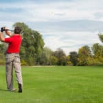 Golfer playing from on a long hole, golf ball visible in the air