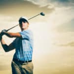 Golfer at sunset, Man swinging golf club with dramatic sunset sky