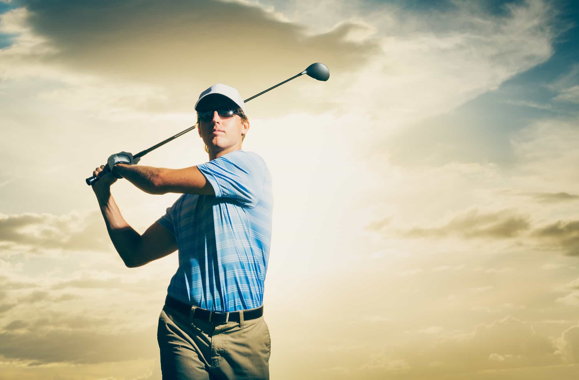 Golfer at sunset, Man swinging golf club with dramatic sunset sky