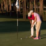 male golf instructor teaching female golf player, personal trainer giving lesson on golf course