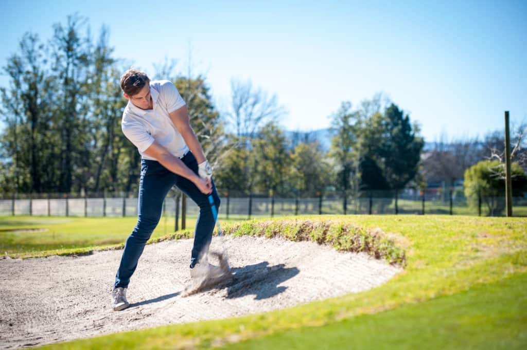 image of a golfer playing a chip shot onto the green on a golf course in south africa