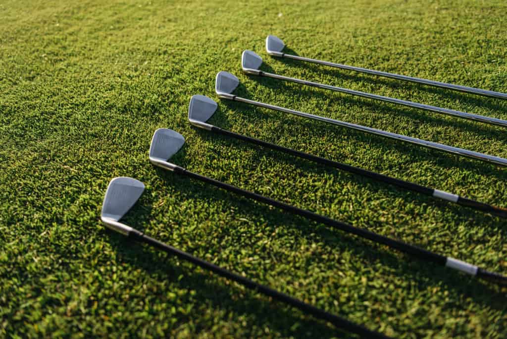 golf club irons lying on grass